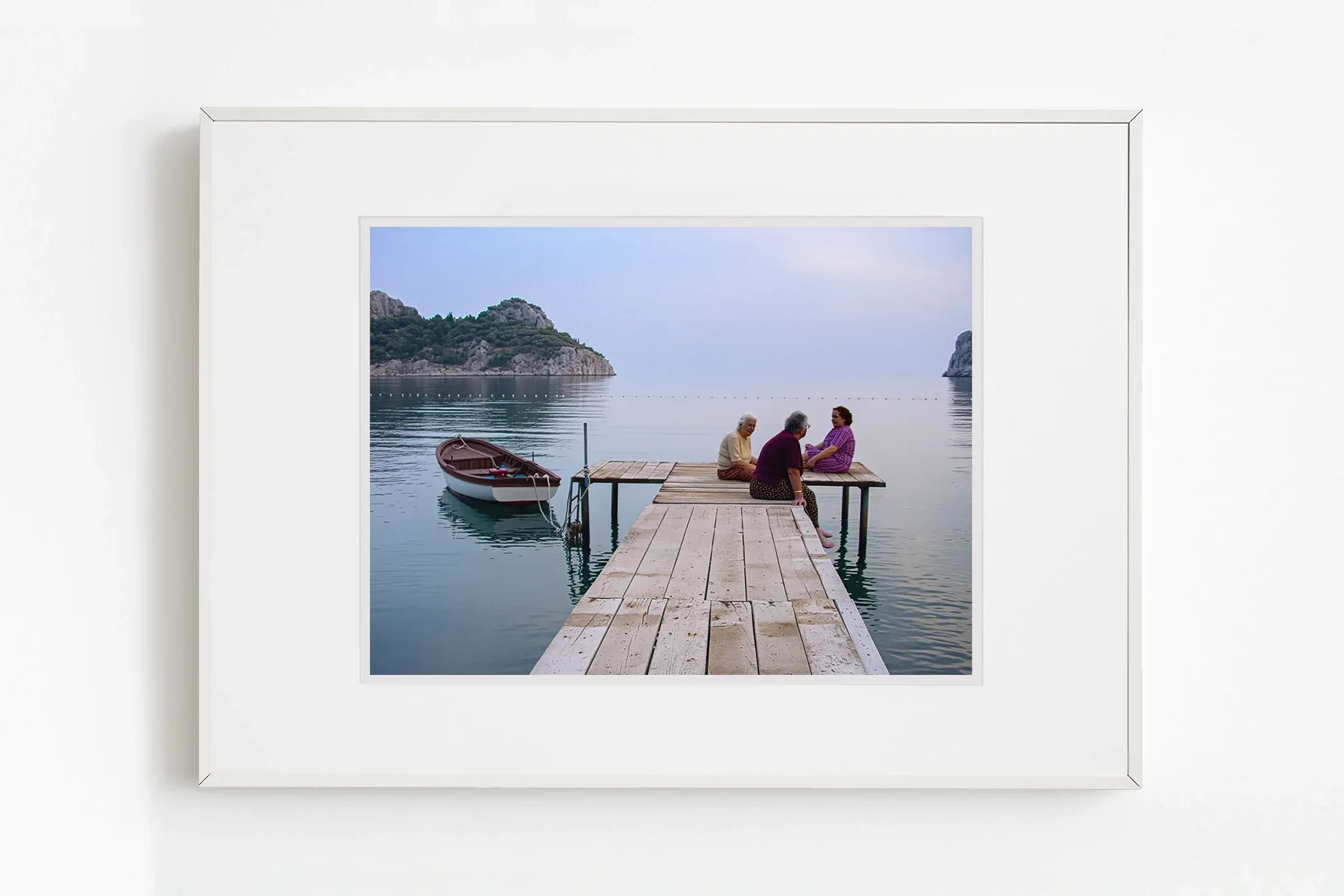 İskele üzerinde yan yana oturan figürlerin sessiz birlikteliğini ele alan fotoğrafik anlatı.