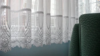 Dantel perde, pencere ve koltuk yüzeyleriyle kurulan sade iç mekân kompozisyonunu gösteren fotoğraf temelli sanat eseri.