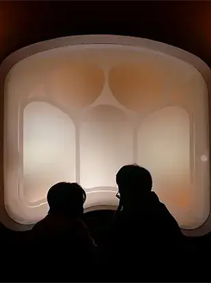 İki siluet, mimarinin taşıyıcı boşluklarını bedenle ölçen bir fotoğraf sanat eseri olarak konumlanır.