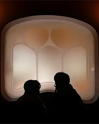 İki siluet, mimarinin taşıyıcı boşluklarını bedenle ölçen bir fotoğraf sanat eseri olarak konumlanır.