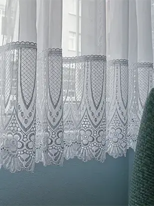 Pencere önünde asılı dantel perde ve süzülen doğal ışığı betimleyen çağdaş fotoğraf sanatı eseri.