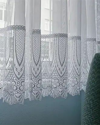 Pencere önünde asılı dantel perde ve süzülen doğal ışığı betimleyen çağdaş fotoğraf sanatı eseri.