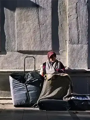 Tarihi türbe önünde duran yaşlı kadını dramatik ışıkla ele alan fotoğrafik anlatı.