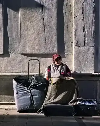 Tarihi türbe önünde duran yaşlı kadını dramatik ışıkla ele alan fotoğrafik anlatı.
